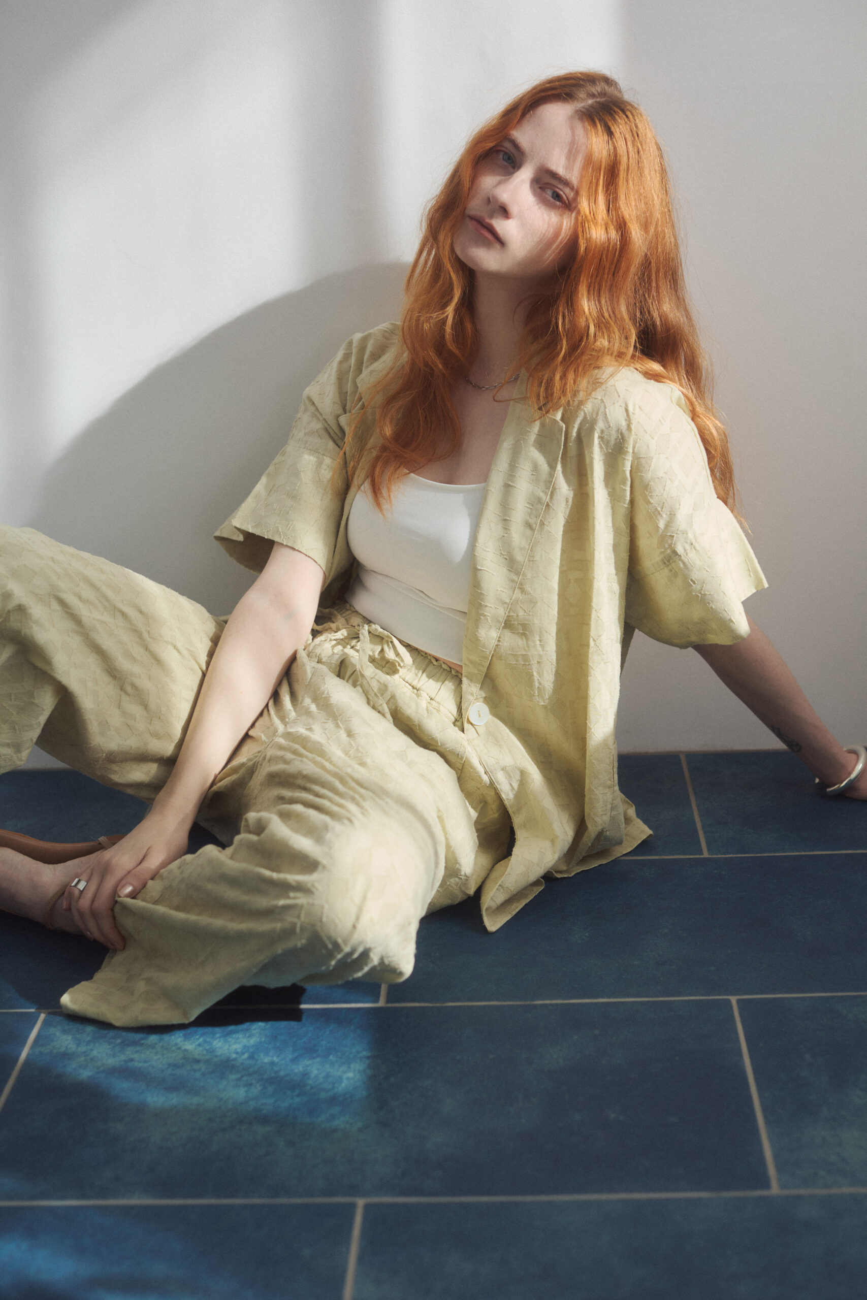 黄色いインド製セットアップを着て床に座っている女性モデル写真