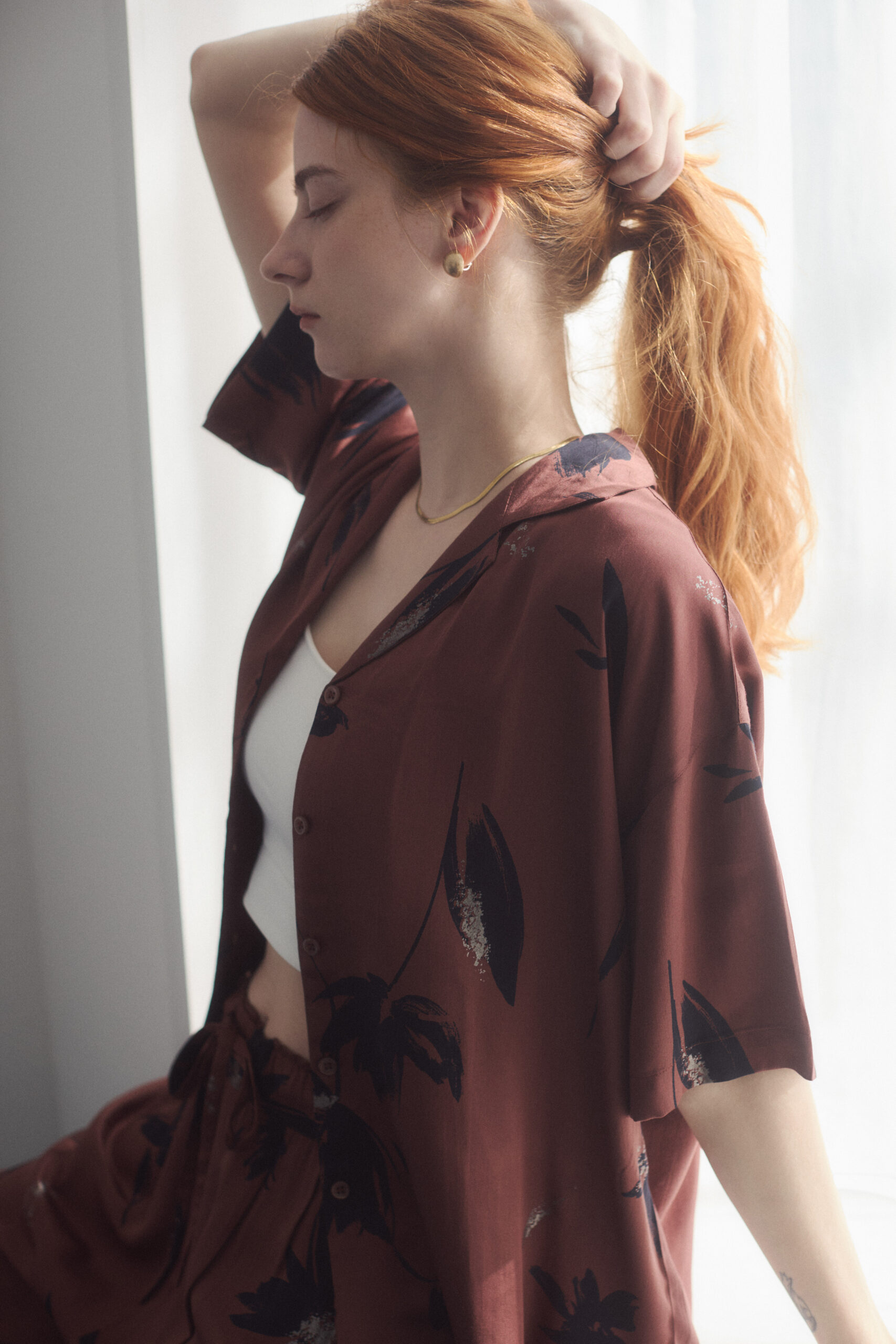 プリント開襟シャツを着て横を向いている女性モデル写真のバストアップ