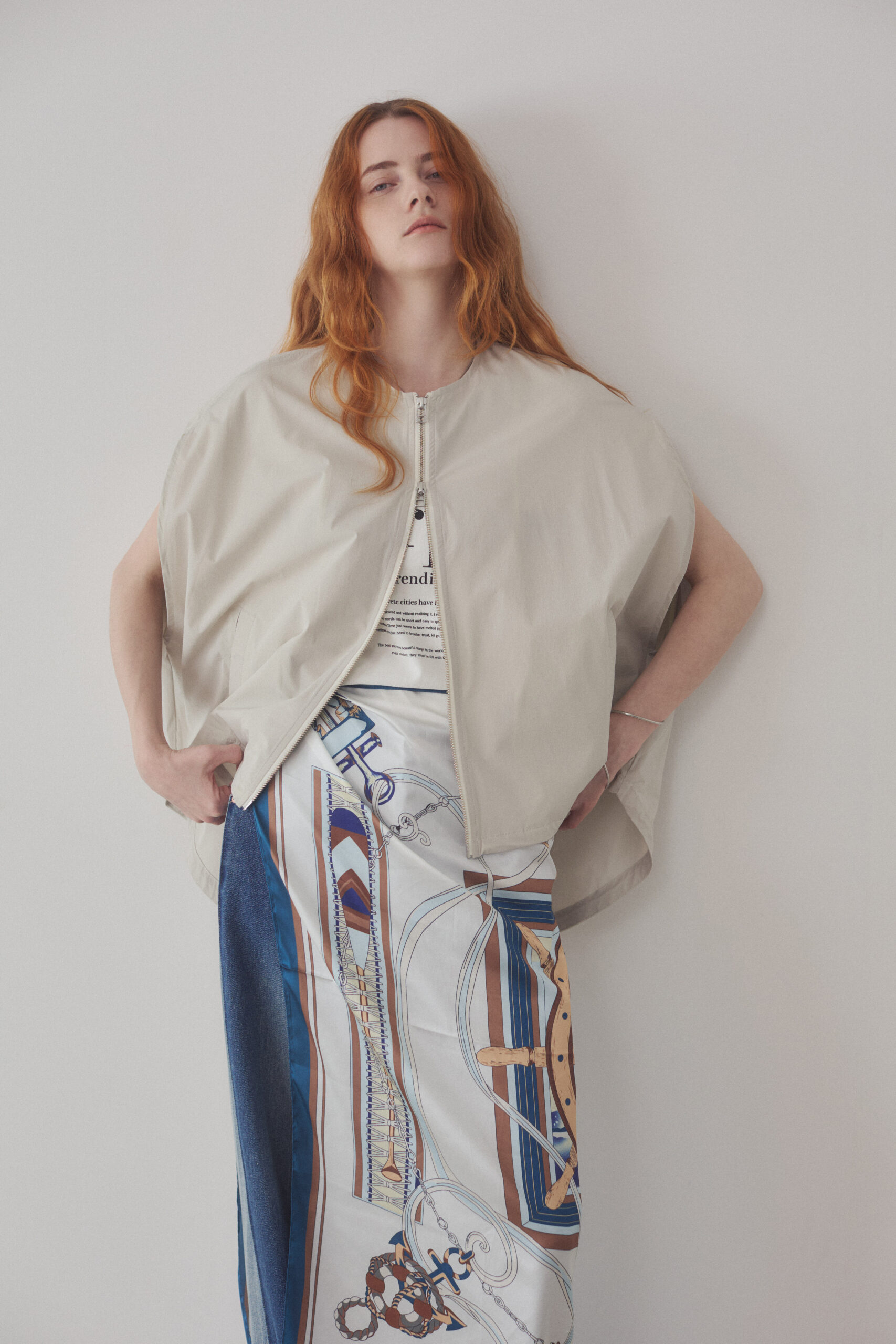 ジッパー付きベストと大判スカーフを腰に巻いている女性モデルの写真