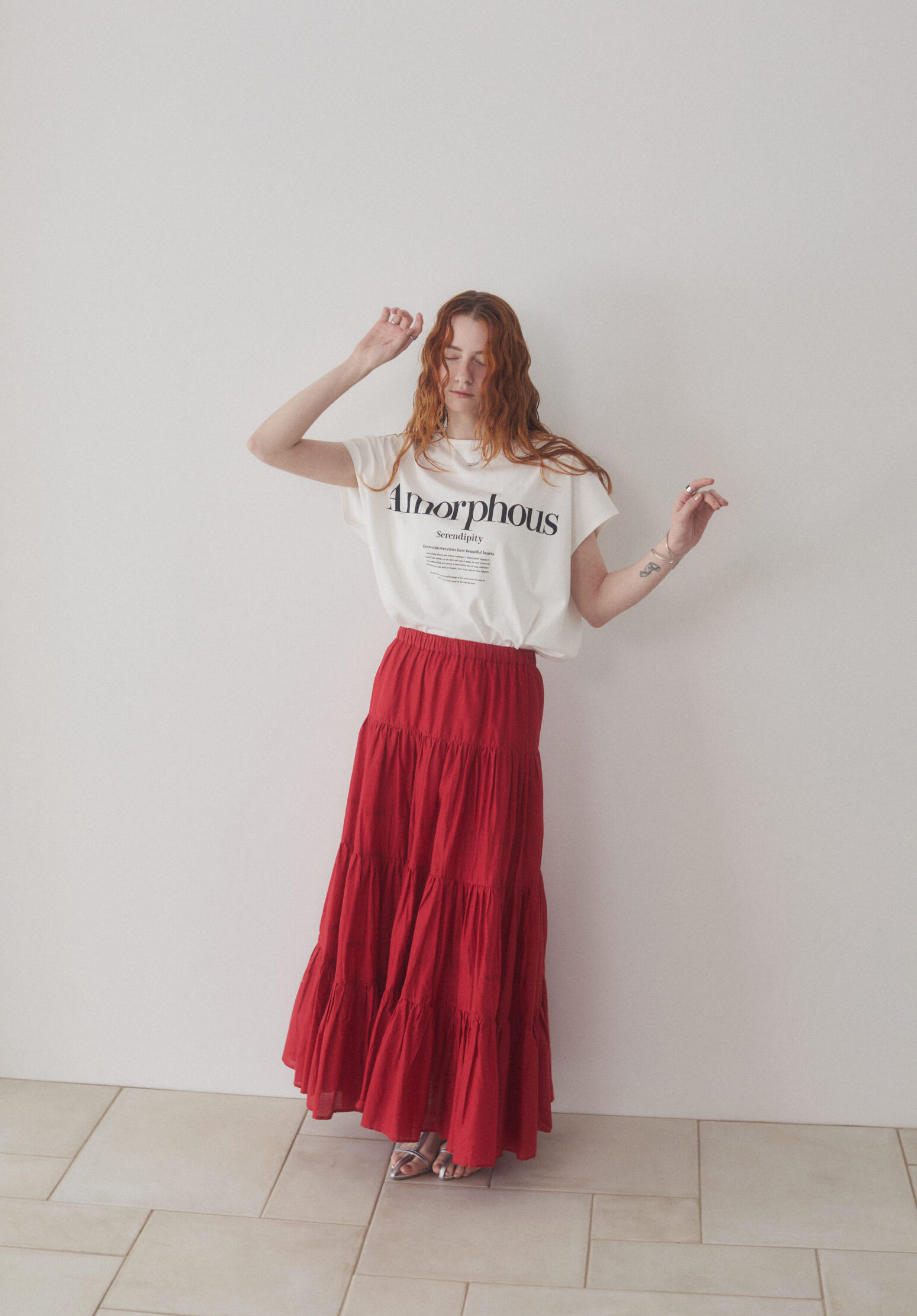 白いＴシャツと赤いマキシティアードスカートを着ている女性モデル写真